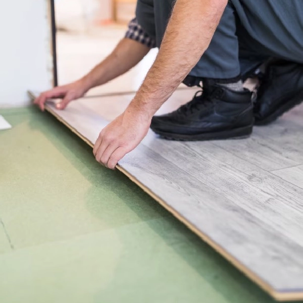 worker installing a light gray wood-look SPC plank