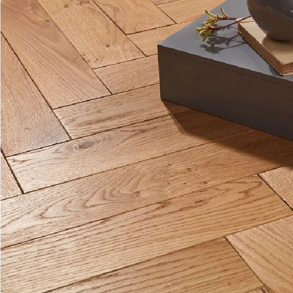 Close-up of natural-toned solid wood flooring planks laid in a herringbone pattern.