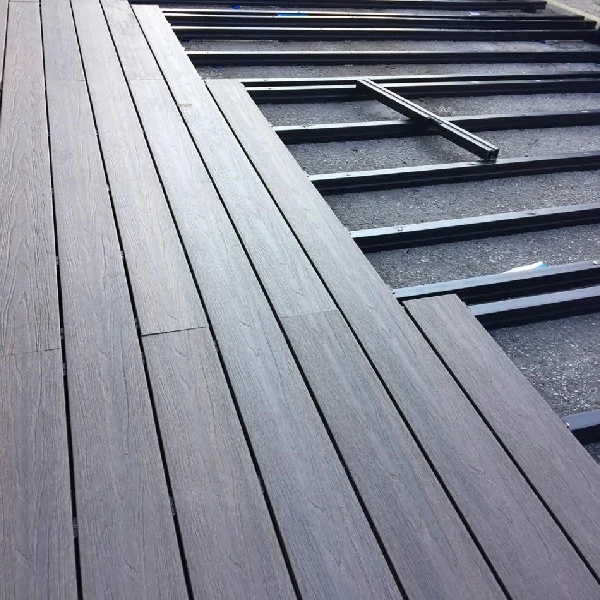 Dark gray WPC decking being installed over a plastic sub-frame