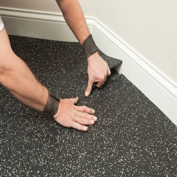 Installing black TPV rubber flooring with white flecks.