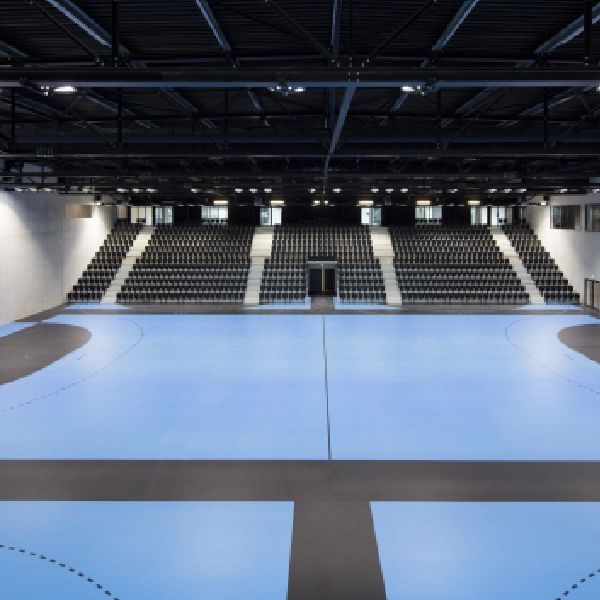Light blue sports arena floor with tiered seating.