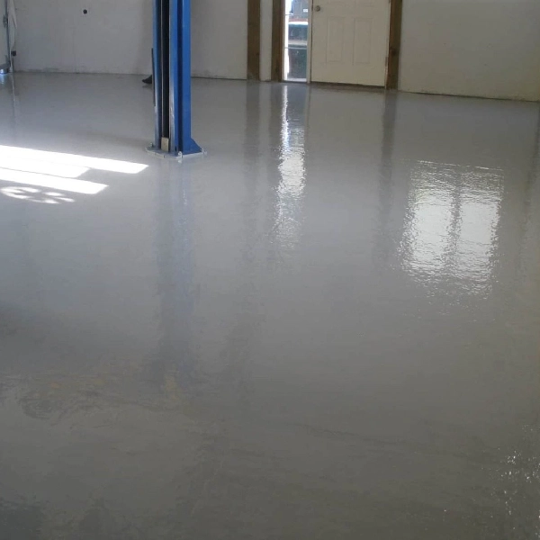 Light gray, glossy epoxy garage floor with car lift.