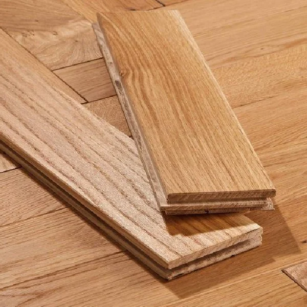 Two interlocking tongue and groove solid wood flooring planks resting on a finished wooden floor.