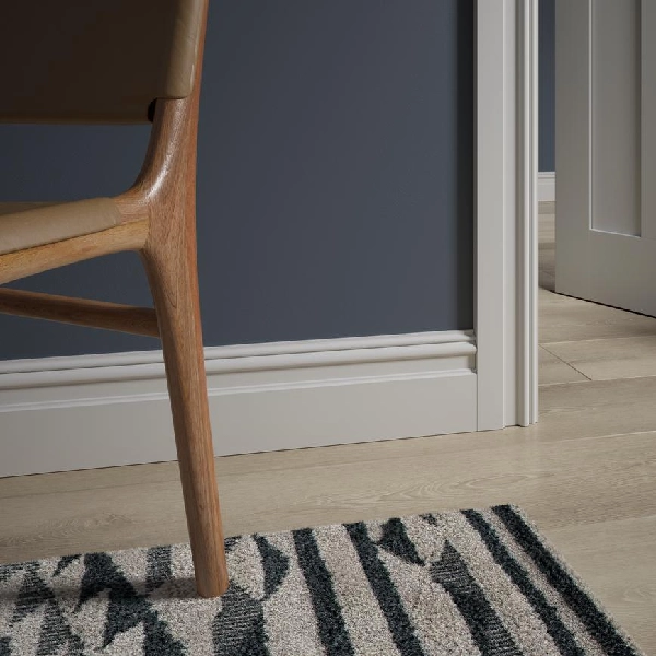 White MDF skirting board with decorative moulding against a deep blue wall
