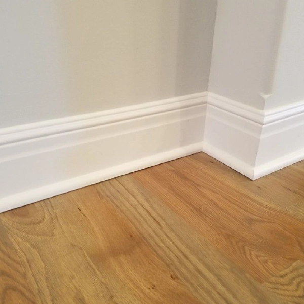 White MDF skirting installed along a wall with wooden flooring