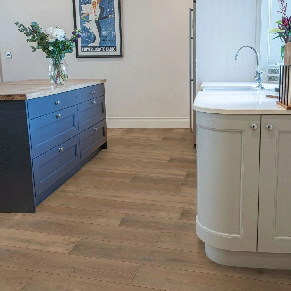 Wood-effect laminate flooring in a kitchen with a blue island and sage cabinet.