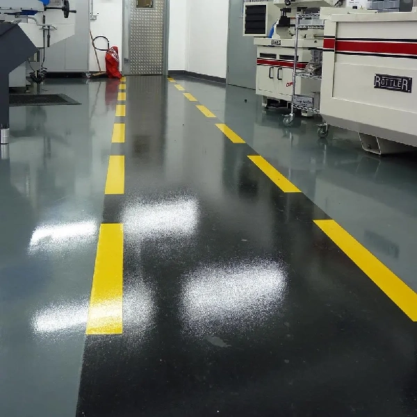 dark gray industrial floor with a dashed yellow line painted on it.