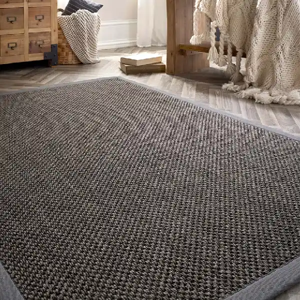 gray sisal rug with a binding, on a wood floor