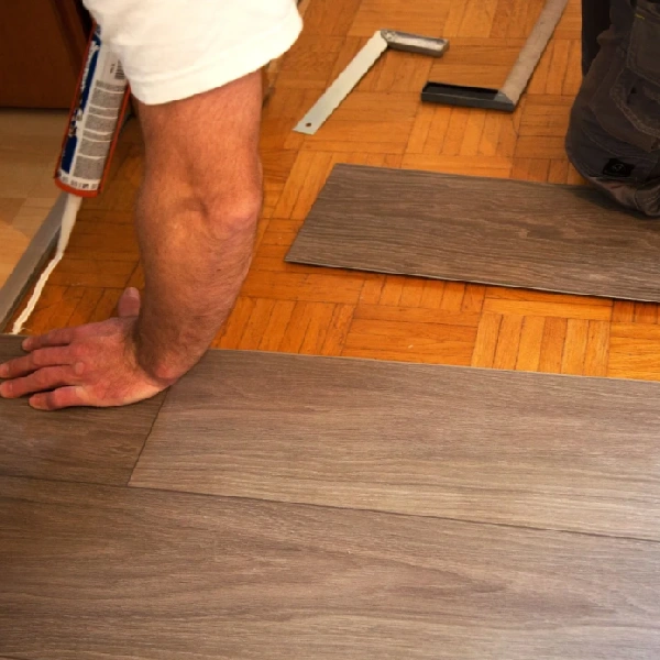 hand pressing down a glue-down wood-plastic composite (WPC) flooring plank