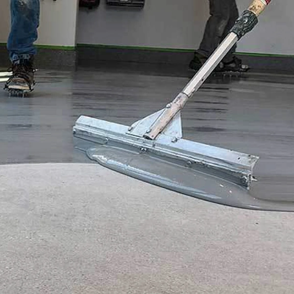 worker spreads thick, gray epoxy coating onto a concrete floor